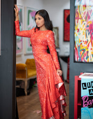 Woman in a red dress standing in a room with colorful artwork on the walls.