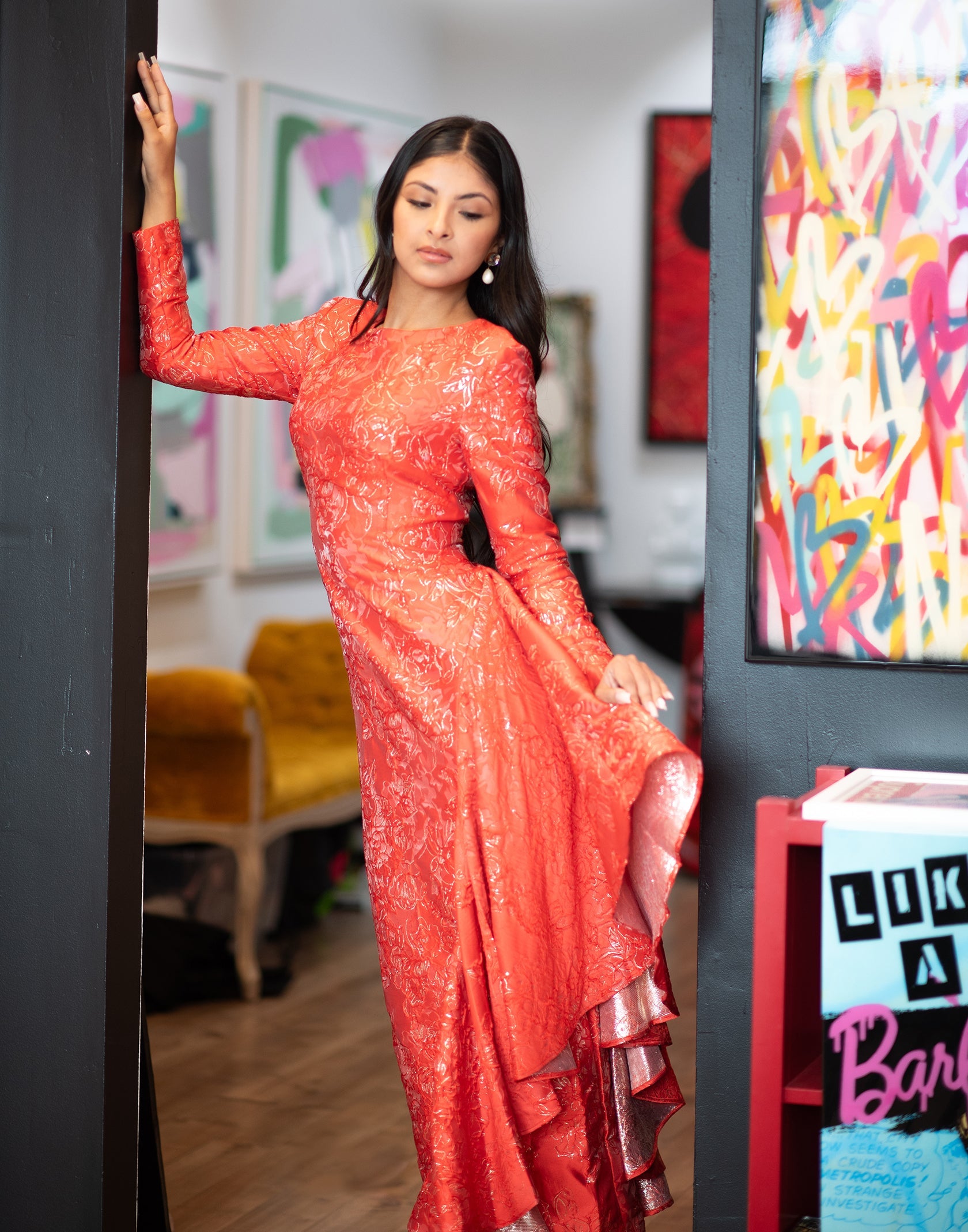 Woman in a red dress standing in an art gallery with colorful paintings.