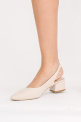 Beige high-heeled shoes worn by a person on a white background