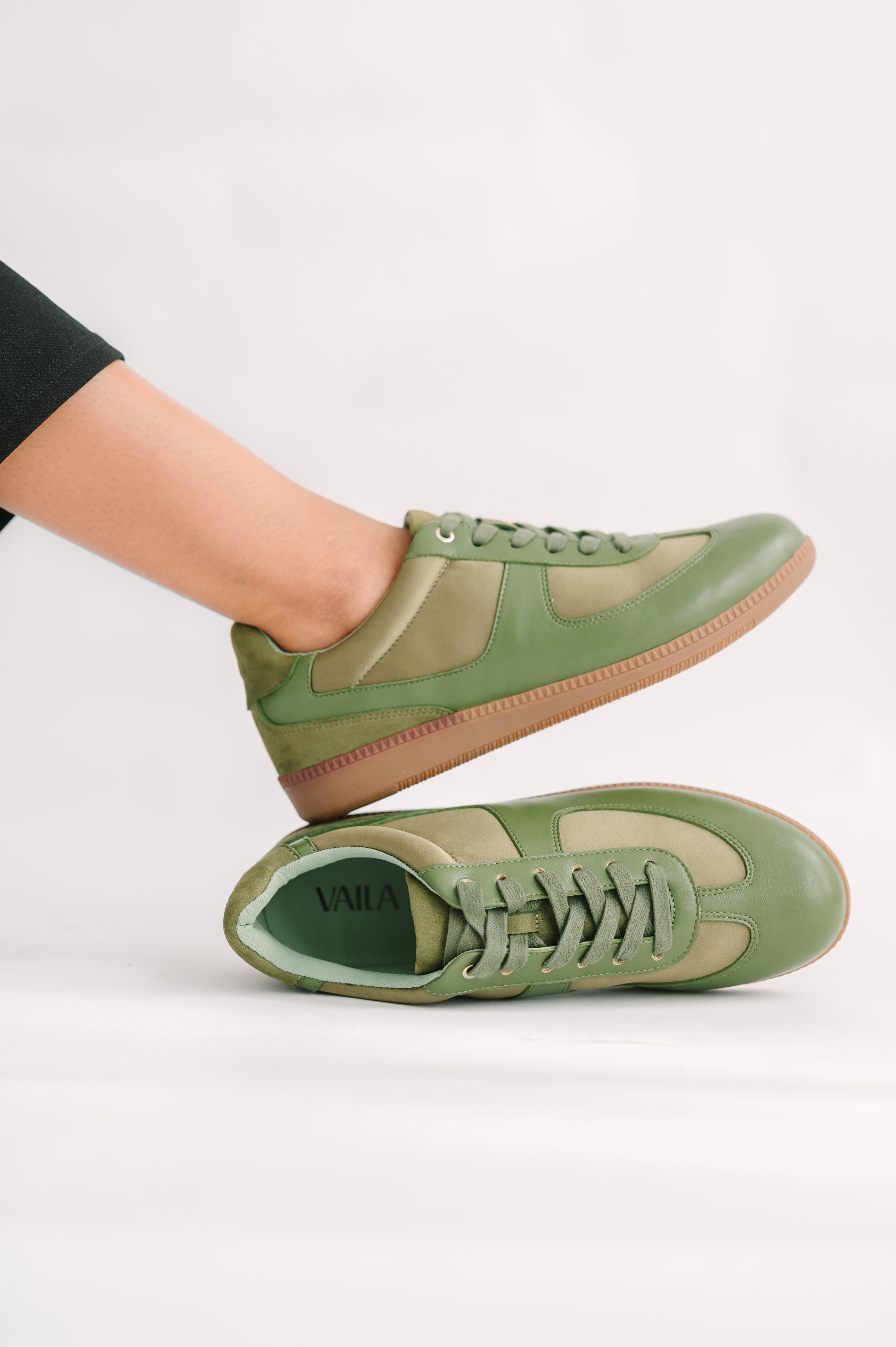 Green sneakers worn by a person on a white background