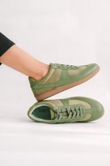 Green sneakers worn by a person on a white background