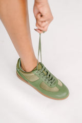 Green sneaker being tied on a white background