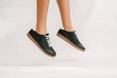 Black sneakers with white laces on a light gray background