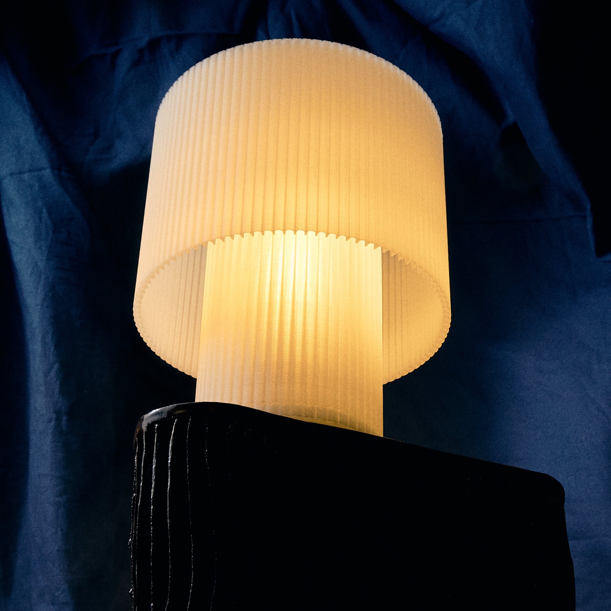 Lamp with pleated shade on a dark blue background