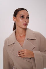 Woman wearing a beige coat against a white background