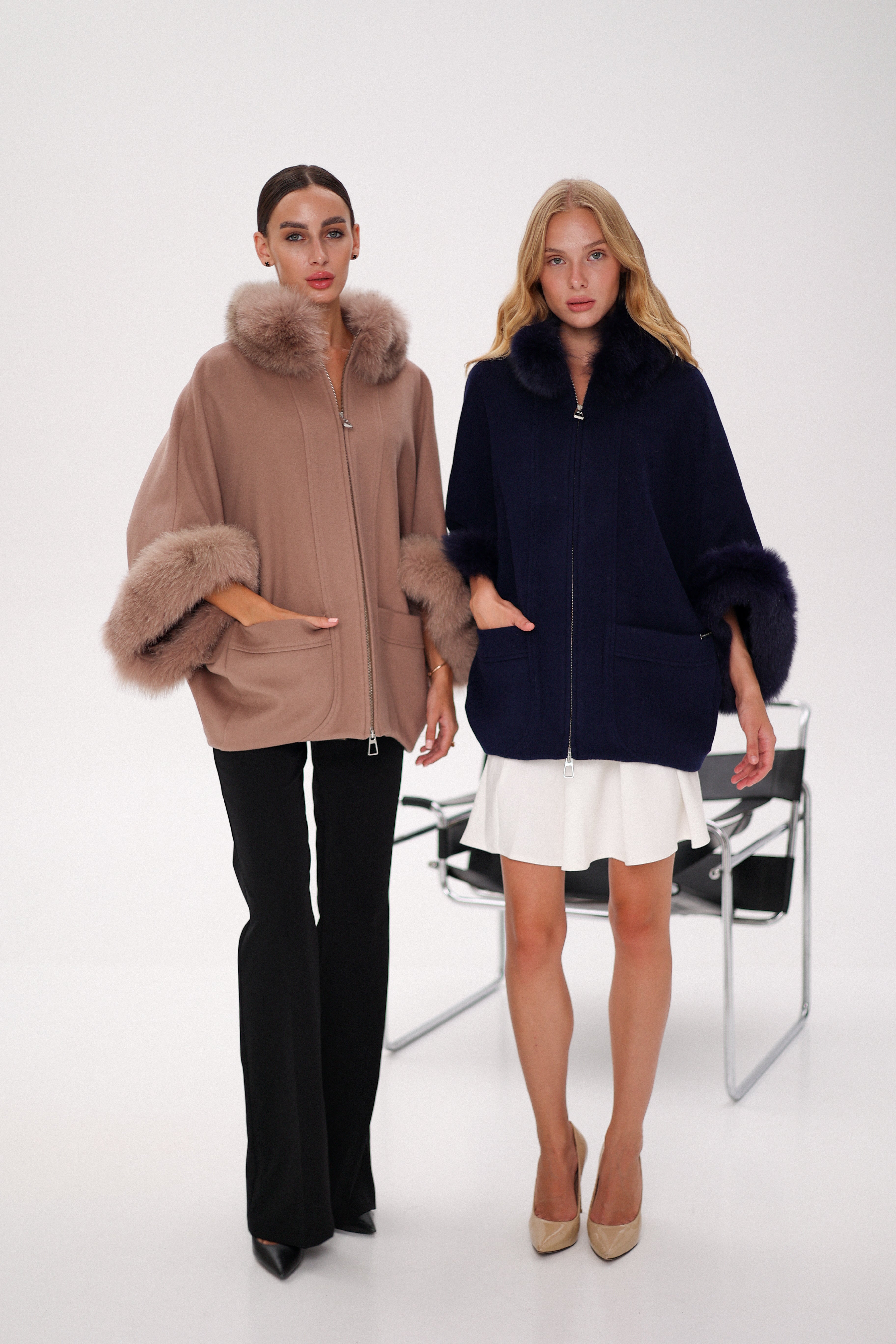 Two women wearing stylish coats with fur trim on a white background