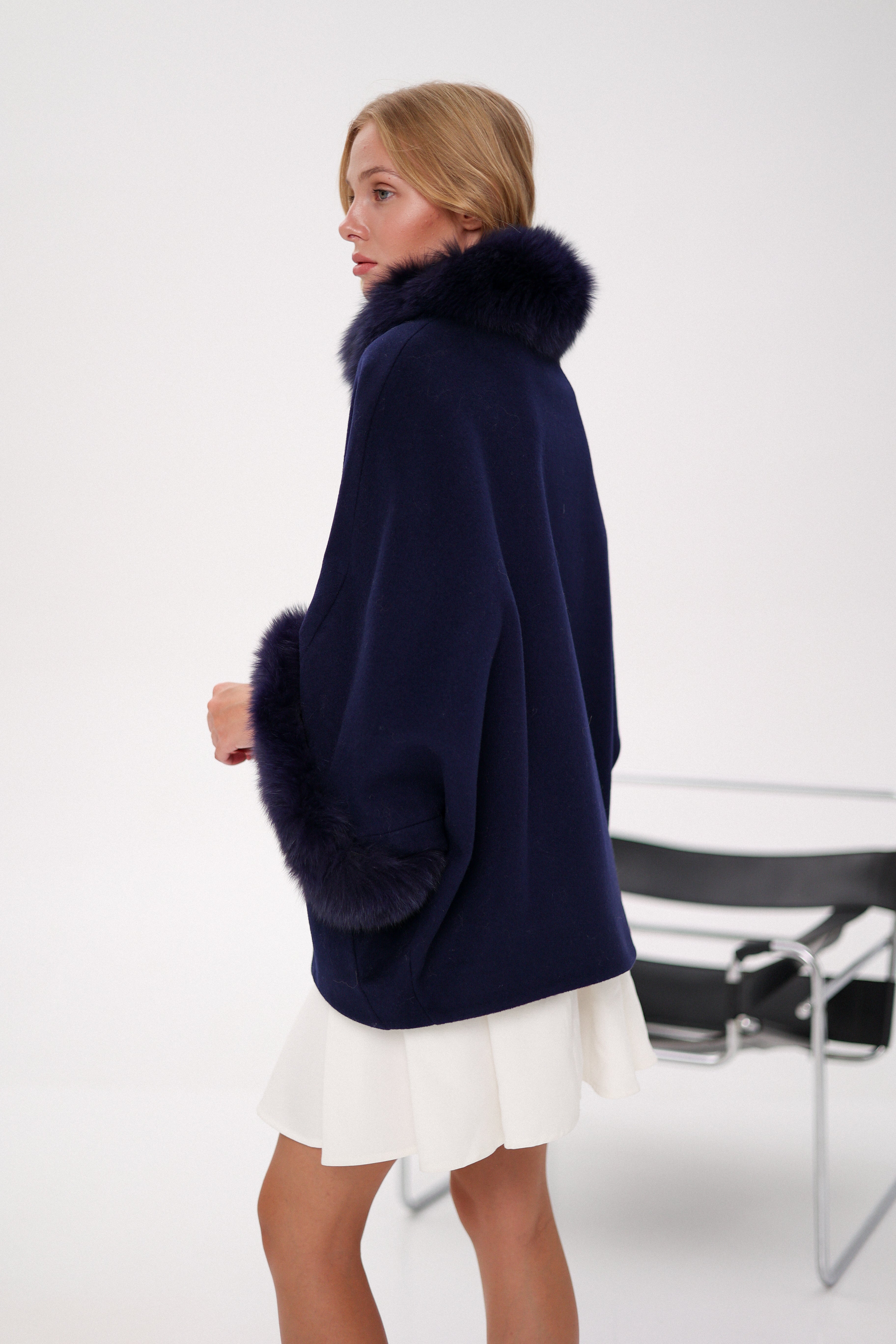 Woman wearing a navy blue sweater with a fur collar on a white background