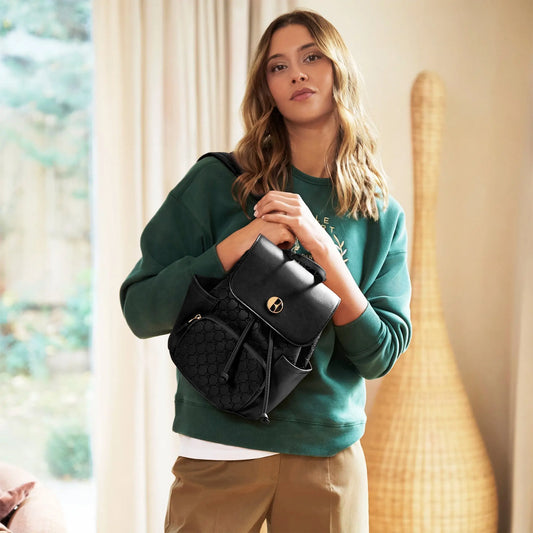 Woman holding a black handbag indoors with a blurred background