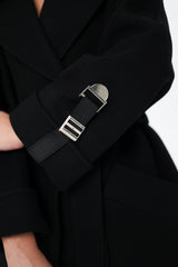 Close-up of a black coat with a silver buckle on a white background