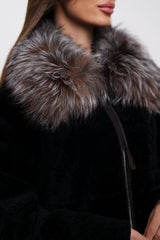 Close-up of a black coat with a fur collar on a neutral background