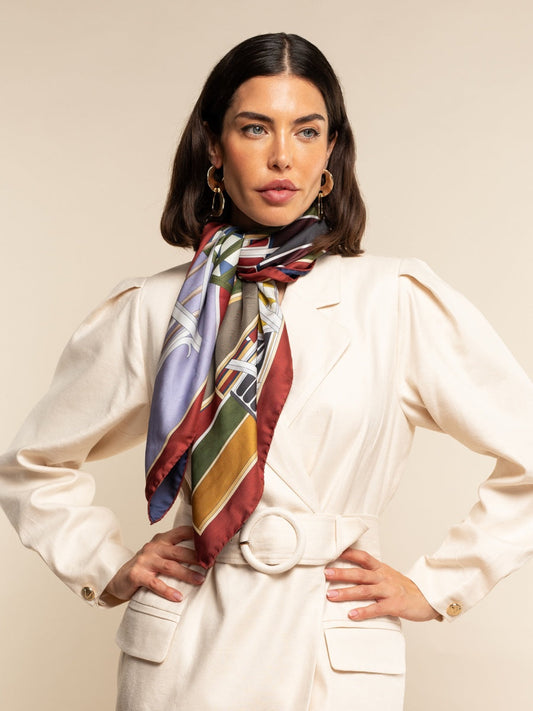 Woman wearing a colorful scarf and white outfit against a plain background