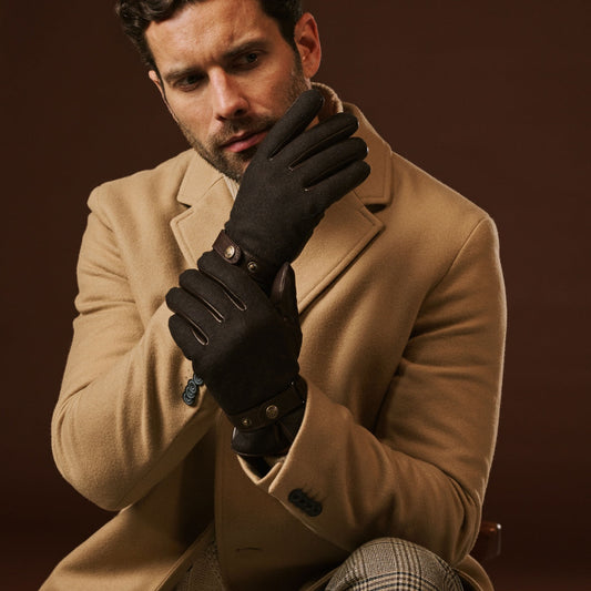Man wearing a beige coat and black gloves against a brown background