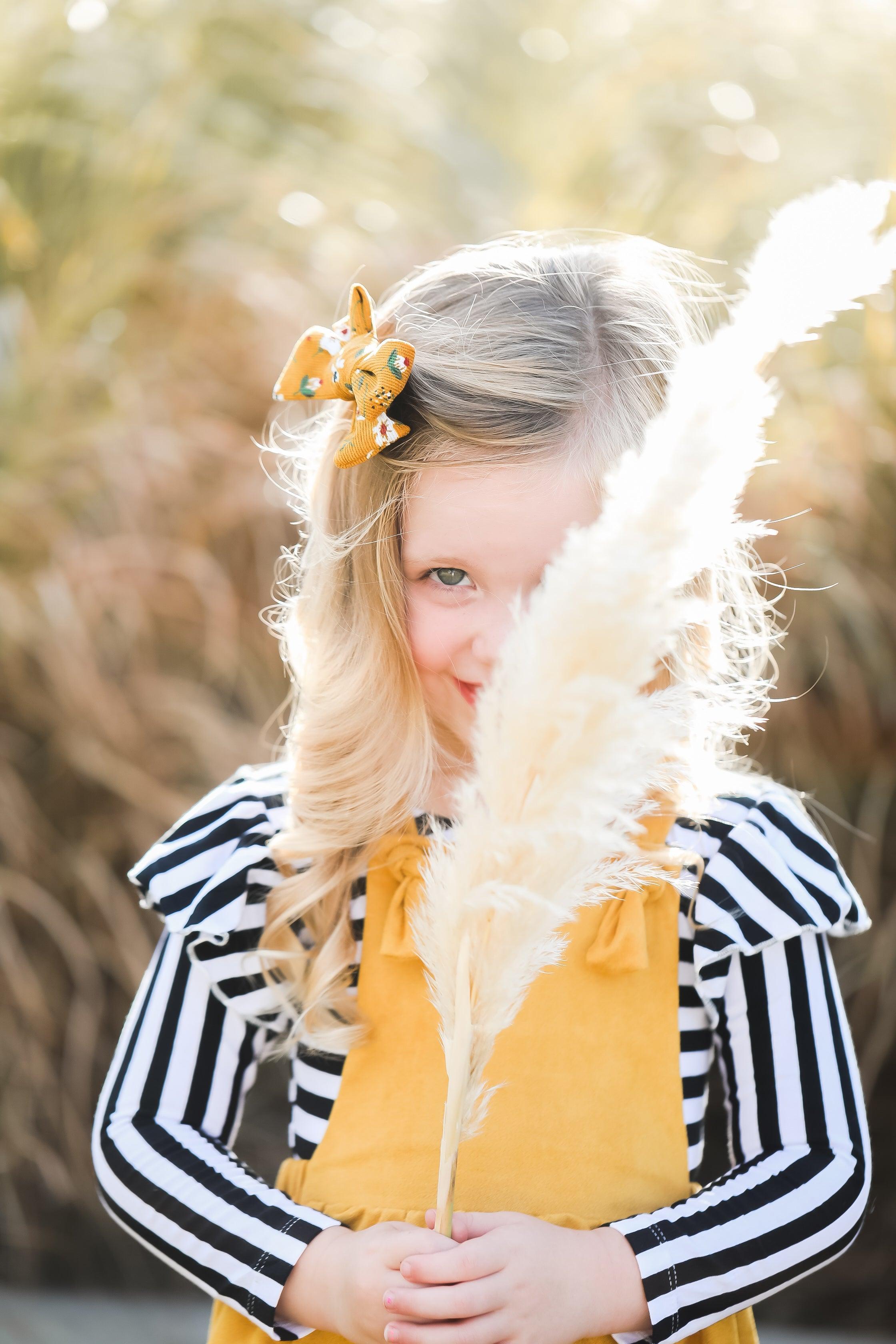 Child holding a decorative pampas grass plant with blurred natural background