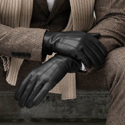 Person wearing black leather gloves with a brown coat and scarf.