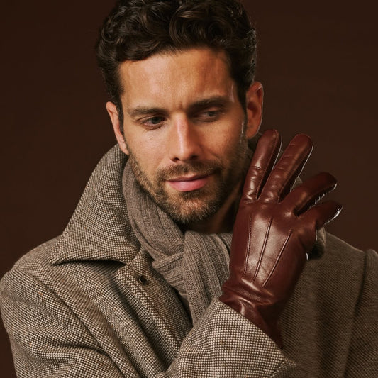 Man wearing a brown leather glove against a dark background