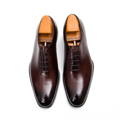 Pair of brown dress shoes with wooden soles on a white background