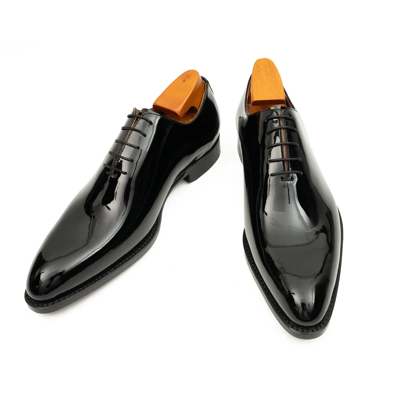 Pair of black dress shoes with orange soles on a white background
