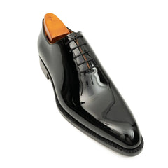 Shiny black dress shoe with orange heel on a white background