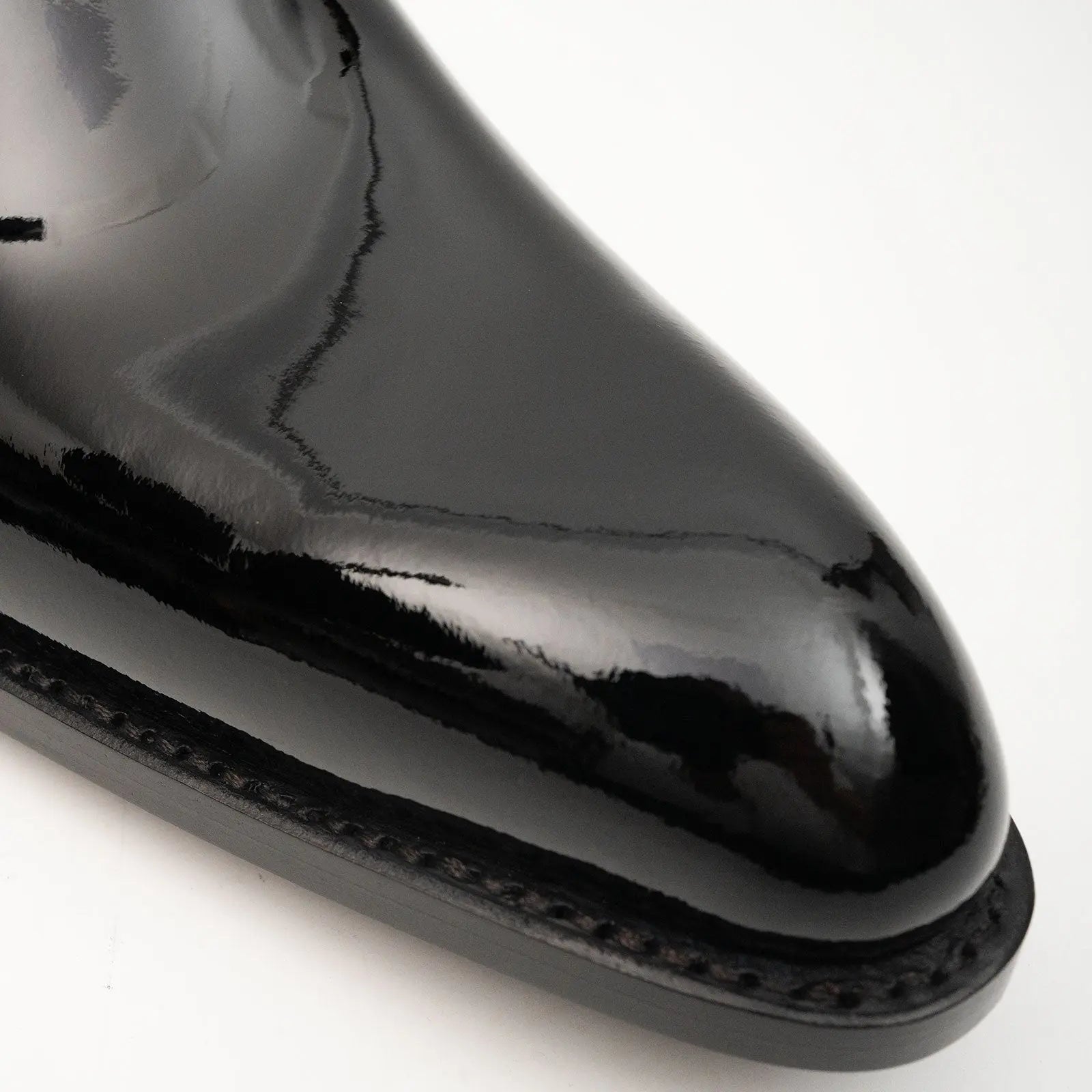 Close-up of a glossy black shoe on a white background
