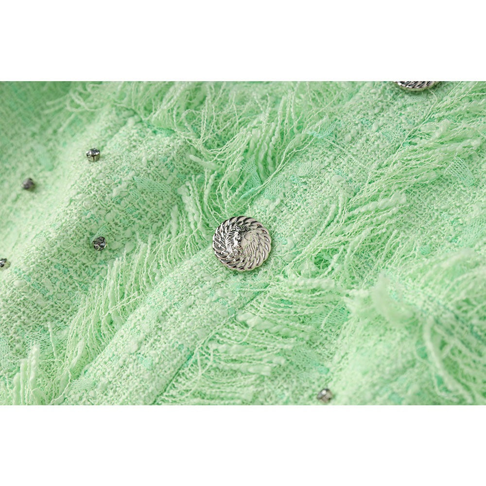 Close-up of a textured green fabric with a metal button on a white background