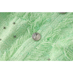 Close-up of a textured green fabric with a metal button on a white background