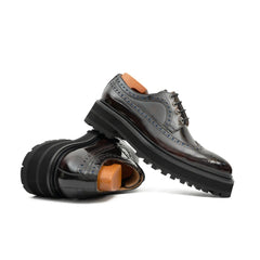 Pair of black leather shoes with brown soles on a white background