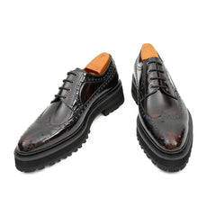 Pair of black leather dress shoes with brown soles on a white background
