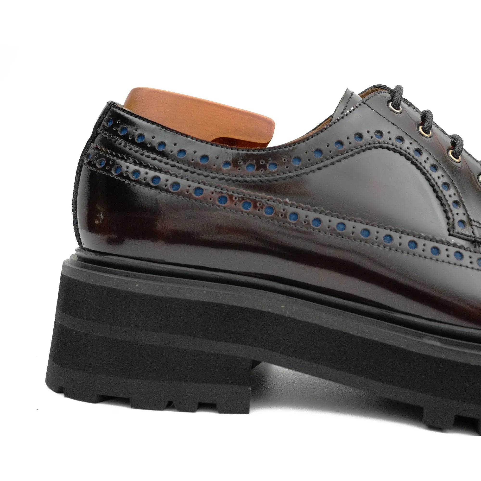 Shiny black leather shoe with a thick sole on a white background