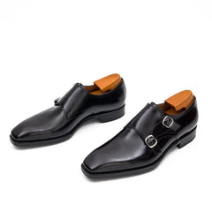 Pair of black dress shoes with brown soles on a white background