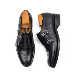 Pair of black leather dress shoes with brown soles on a white background
