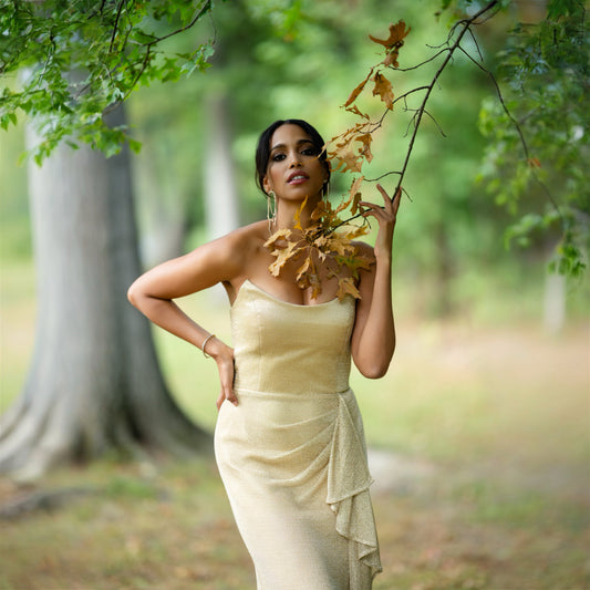 Woman in a light dress holding leaves in a forest setting