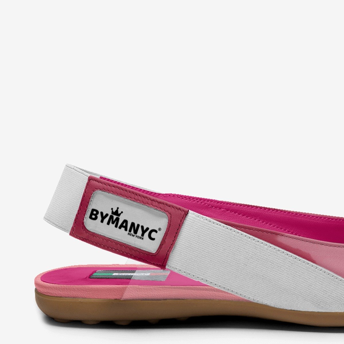 Pink slip-on shoe with white strap and 'BYMANYC' label on a white background