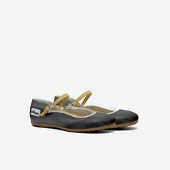 Black flat shoes with tan straps on a white background