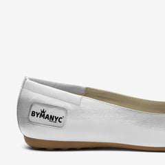 White flat shoe with brown sole and 'BYMANYC' logo on a white background