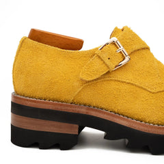 Yellow suede shoe with a buckle on a white background