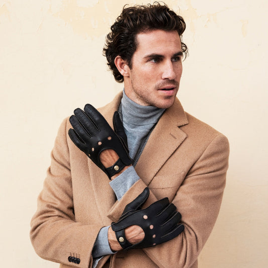 Man wearing a tan coat and black gloves against a beige background