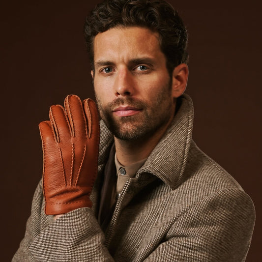 Man wearing a brown leather glove against a dark background