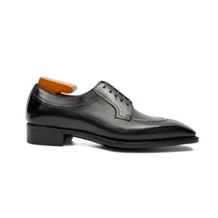 Black dress shoe with wooden insole on a white background