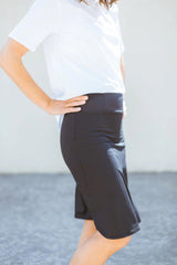 Person wearing a white shirt and black skirt against a neutral background
