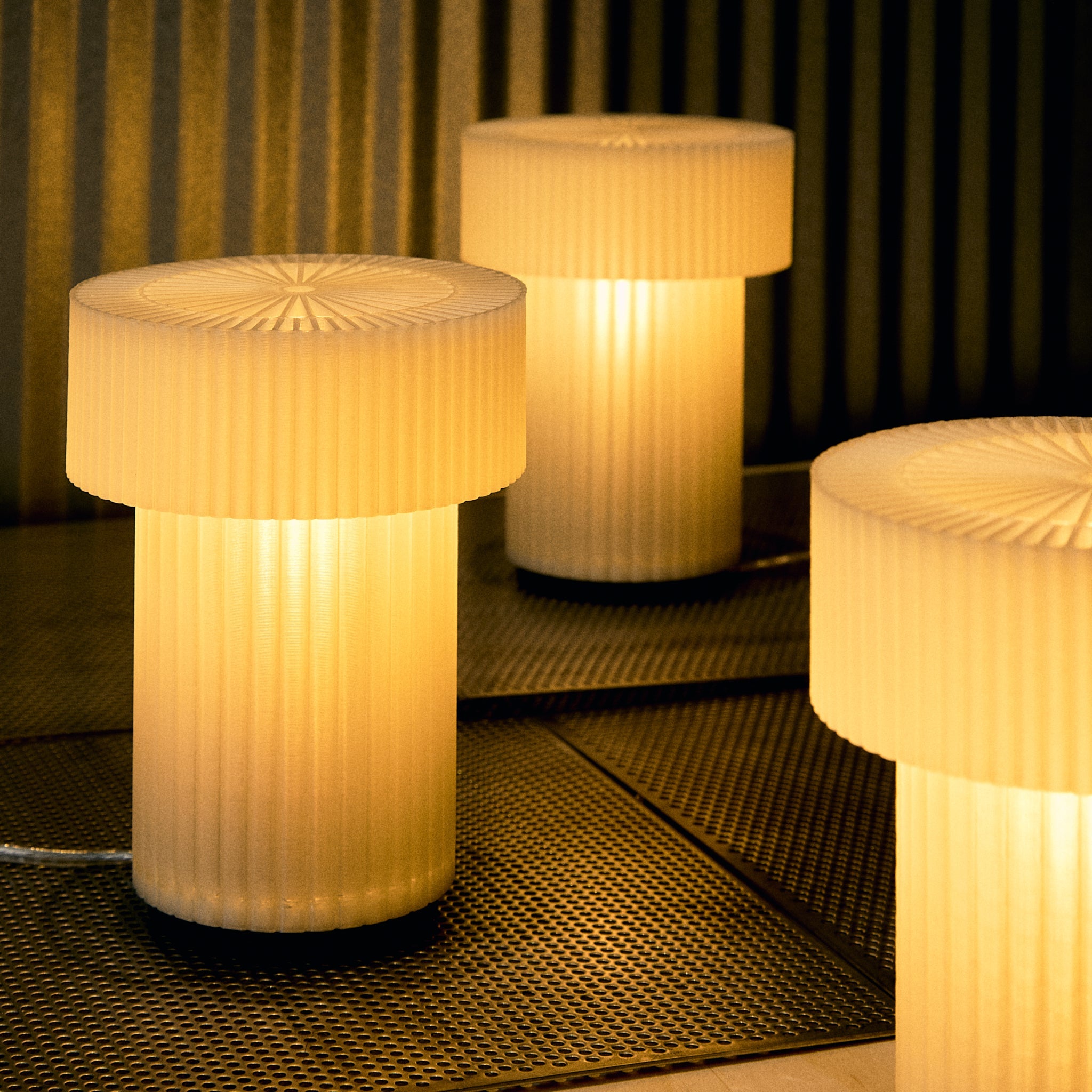 Three cylindrical lamps with textured surfaces on a dark woven surface.