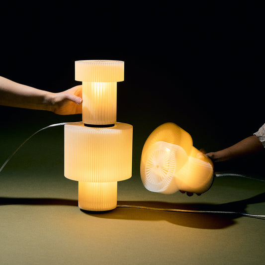 Two hands holding a textured lamp with a dark background