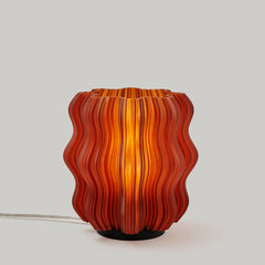 Decorative lamp with wavy orange and red design on a light gray background