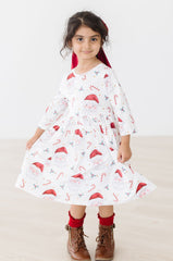 Young girl wearing a white dress with red patterns on a white background