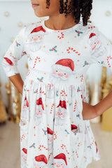 Child wearing a white dress with Santa Claus print in a festive setting