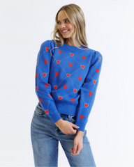 Woman wearing a blue sweater with red heart patterns on a white background