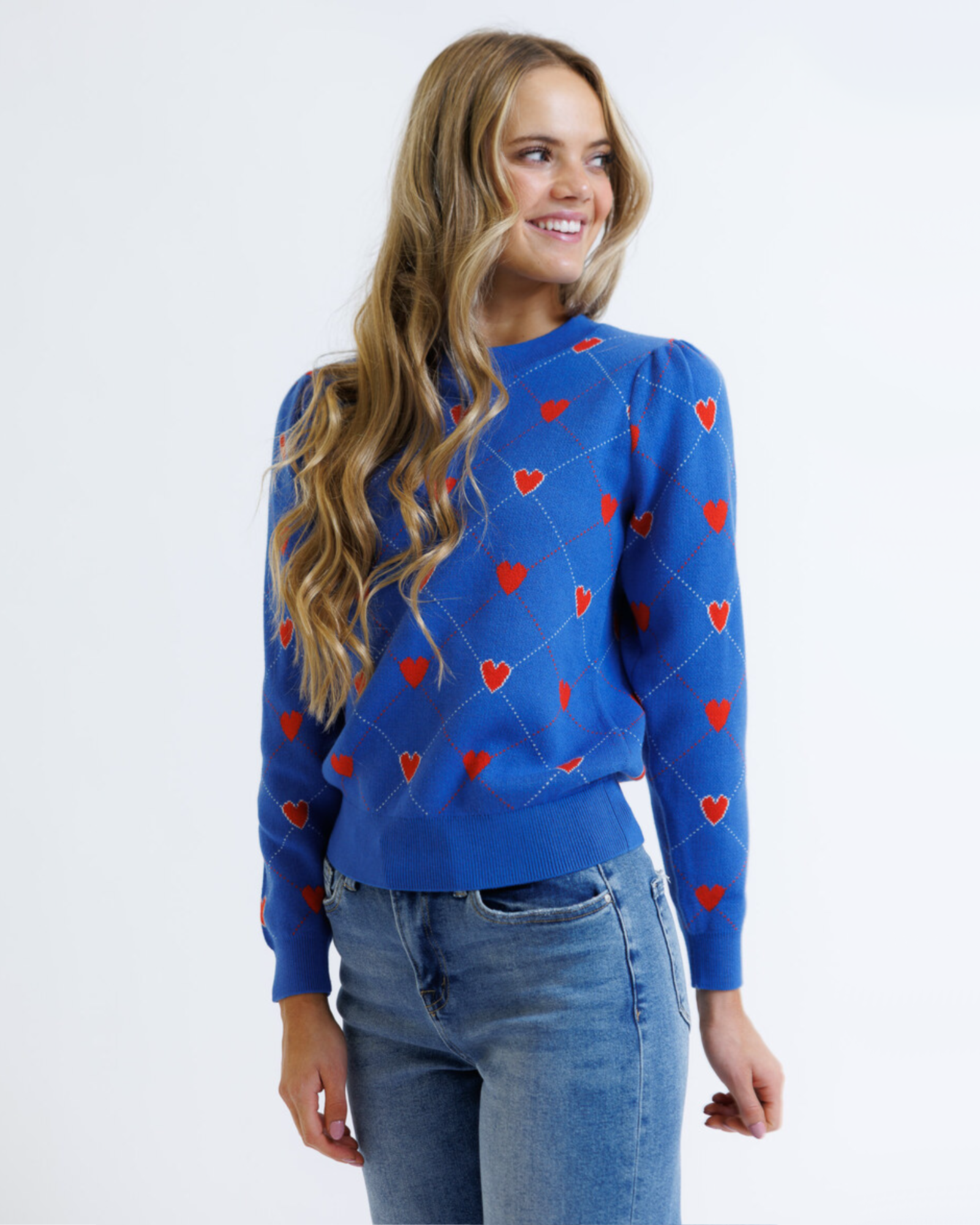 Woman wearing a blue sweater with red heart patterns on a white background