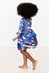 Person wearing a blue dress with pink floral patterns on a white background