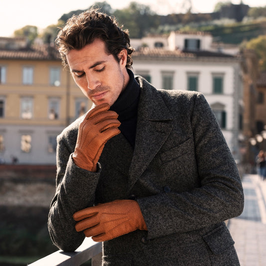 Man wearing a gray coat and brown gloves in an urban setting