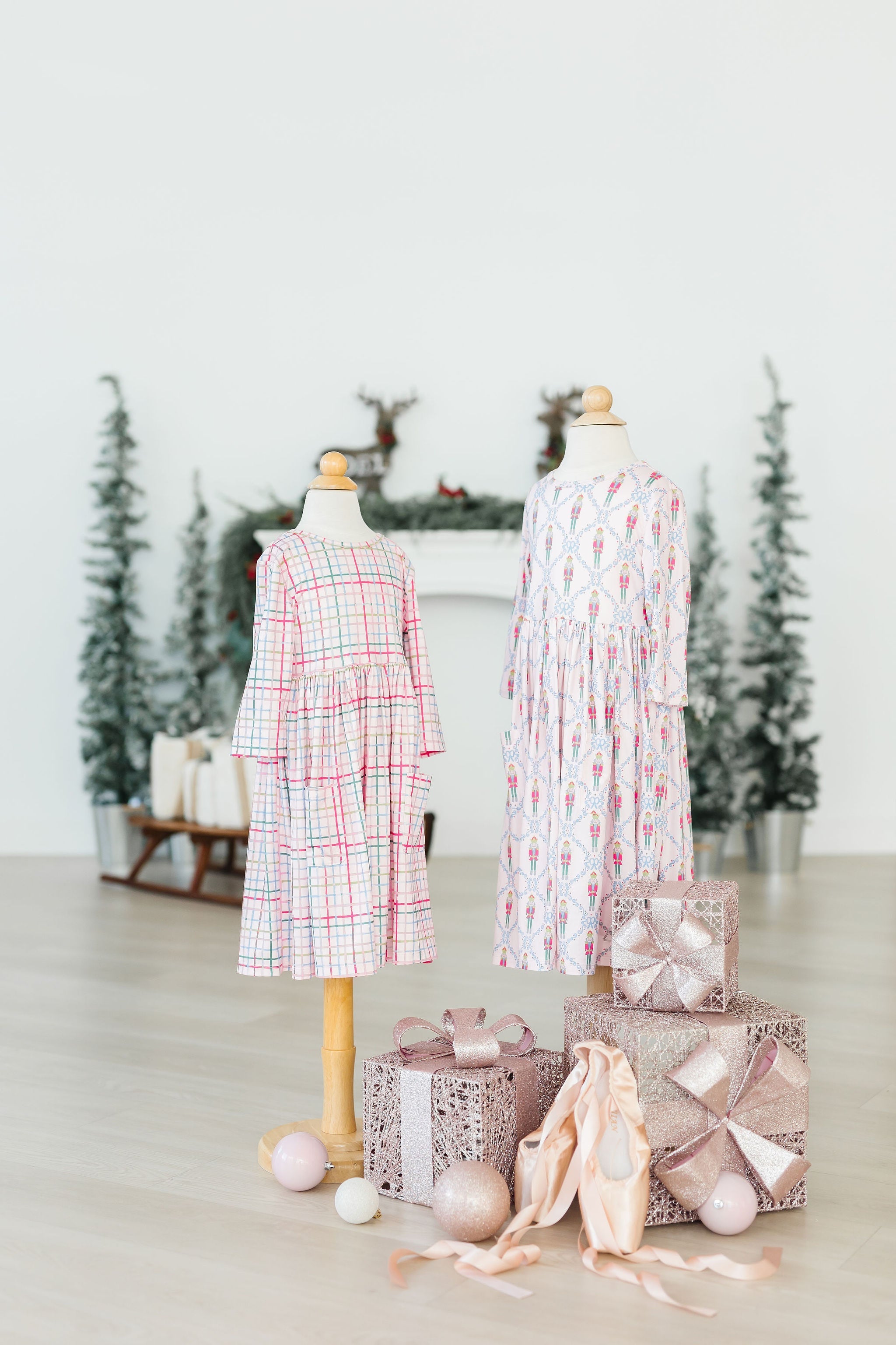 Two mannequins wearing dresses with decorative eggs and gift boxes on a light background