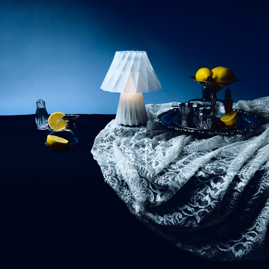 Lamp on a table with lemons and lace fabric under a blue light